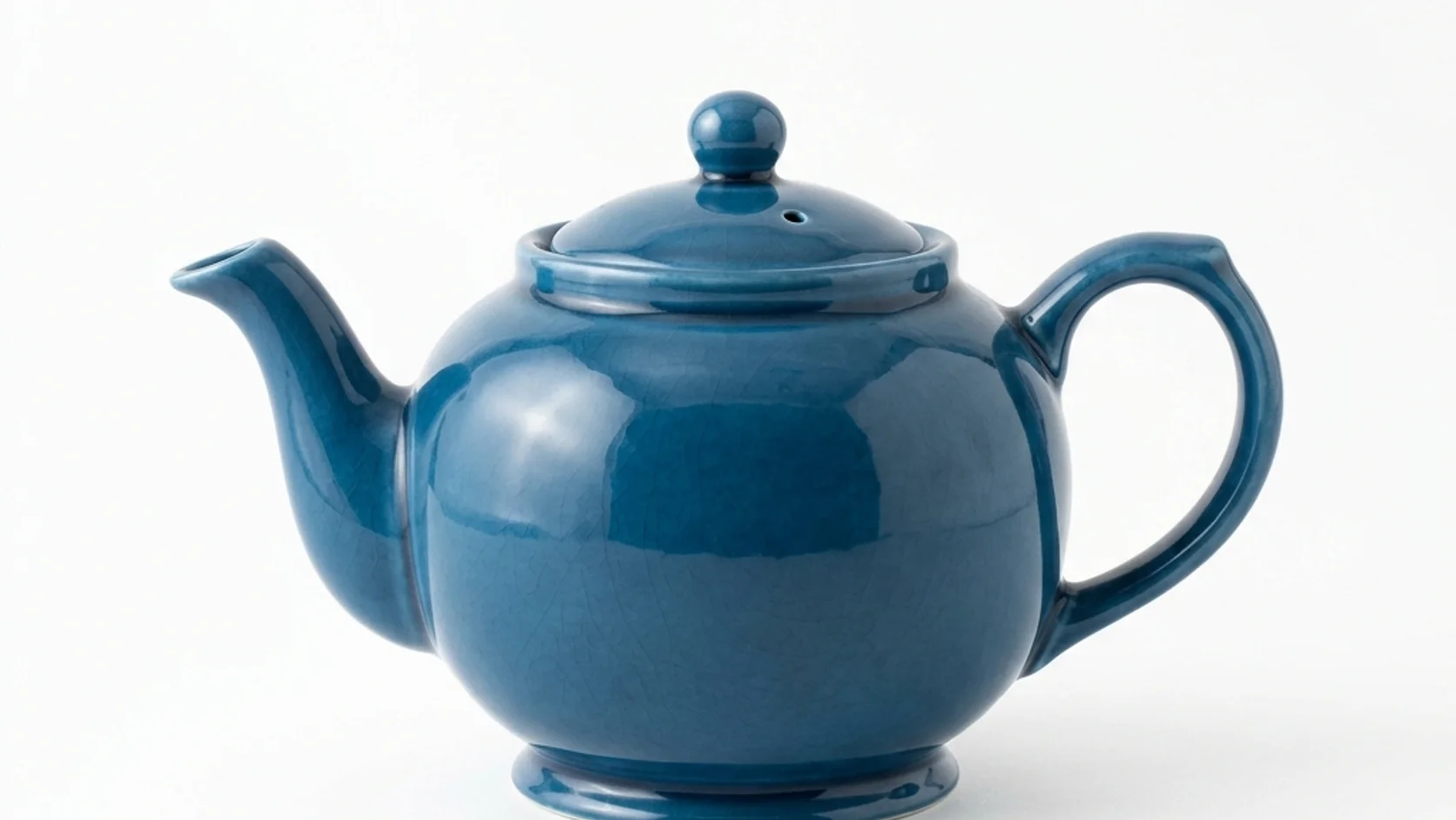 Blue ceramic teapot isolated against a pale background.