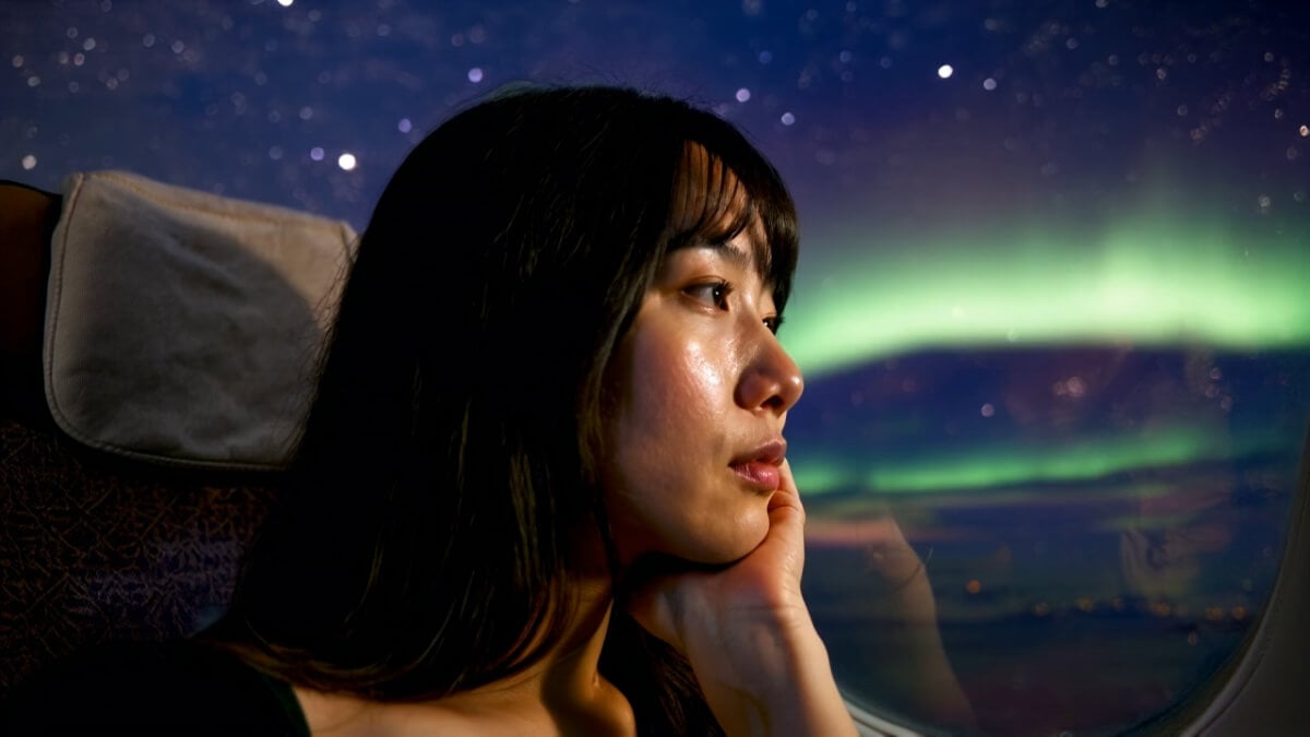 Woman looking at an aurora in the night sky.